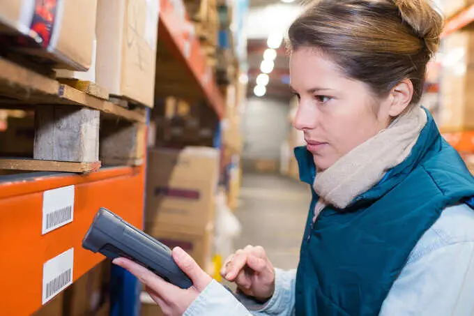 L’étiquetage industriel : traçabilité et qualité de production 1 Employée de logistique scannant une étiquette à code barre